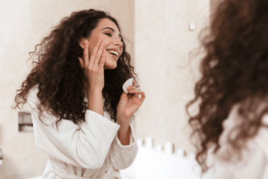 image of woman applying cream for acne | article about adapalene vs benzoyl peroxide