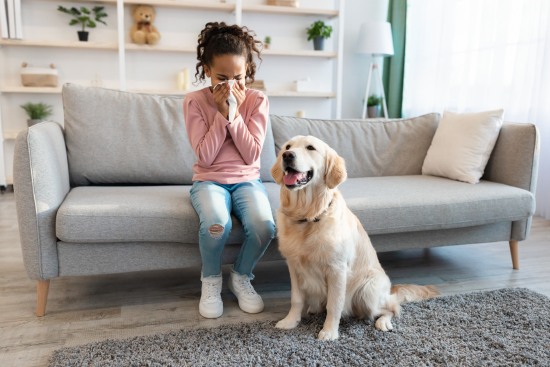 woman sitting on couch blowing nose next to a dog