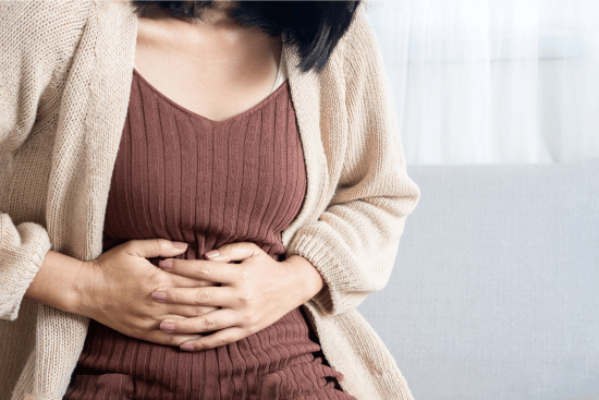 person holding stomach in pain - comparing gas and heartburn medicines